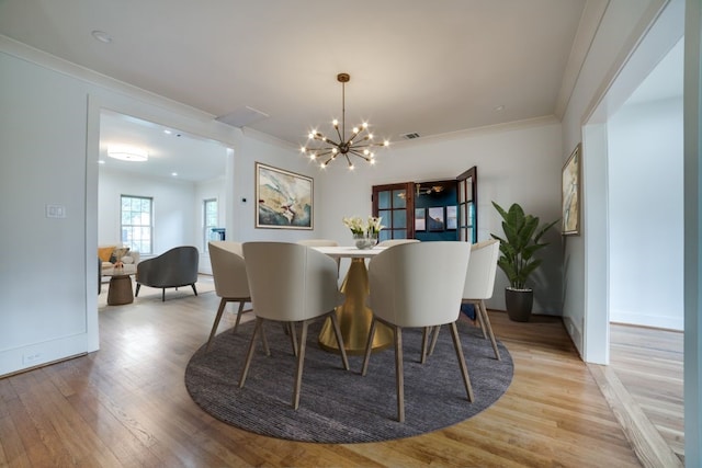 dining area featuring a chandelier, ornamental molding, and light hardwood / wood-style flooring