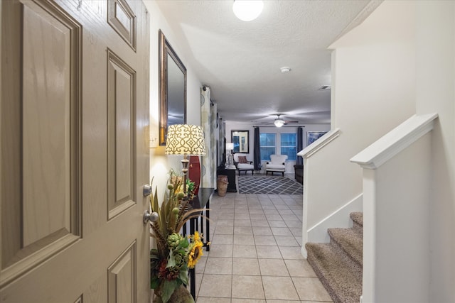 tiled foyer entrance with ceiling fan and a textured ceiling