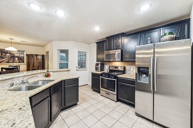 kitchen featuring a textured ceiling, sink, stainless steel appliances, and hanging light fixtures