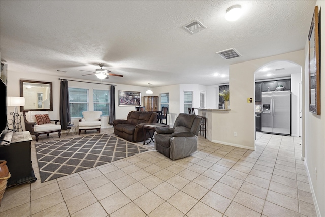 tiled living room featuring ceiling fan and a textured ceiling