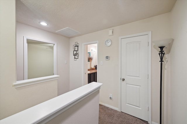 hallway with carpet floors and a textured ceiling