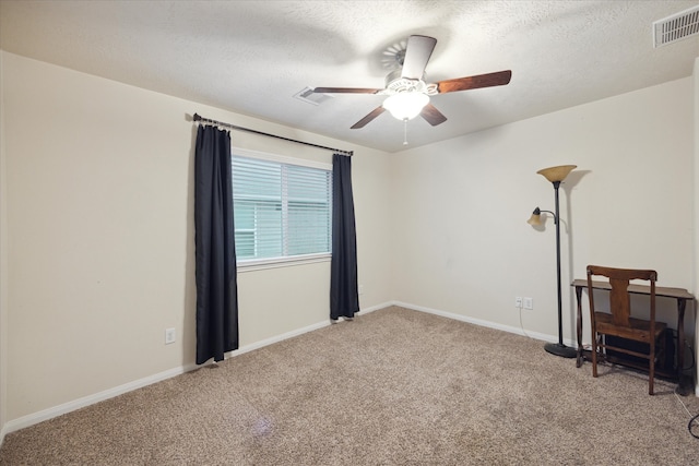 empty room with ceiling fan, carpet floors, and a textured ceiling