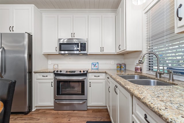 kitchen with white cabinetry, sink, light stone countertops, dark hardwood / wood-style flooring, and appliances with stainless steel finishes