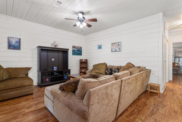 living room with wood-type flooring, ceiling fan, crown molding, and wood walls