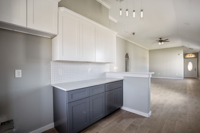 kitchen with white cabinets, kitchen peninsula, dark hardwood / wood-style flooring, and backsplash