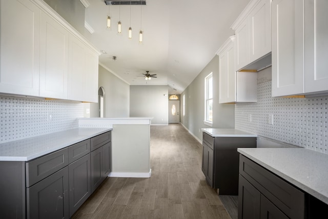 kitchen featuring white cabinets, wood-type flooring, tasteful backsplash, and decorative light fixtures