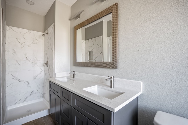 bathroom featuring vanity, toilet, and tiled shower