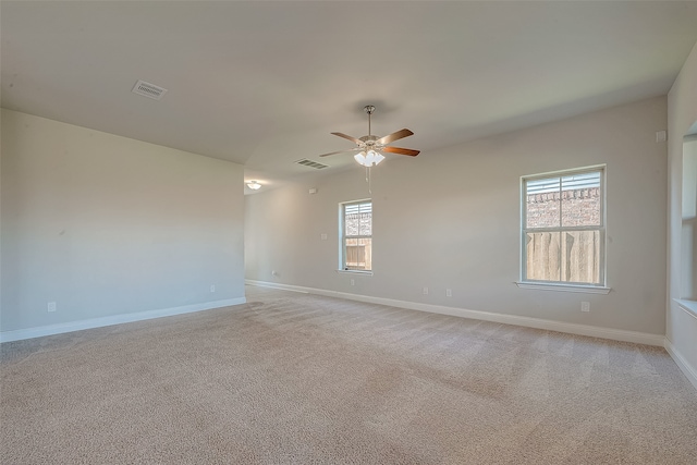 carpeted spare room featuring ceiling fan and a healthy amount of sunlight