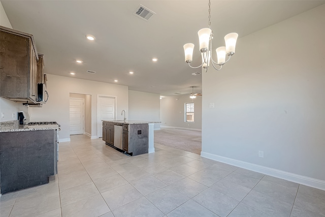 kitchen featuring light stone countertops, sink, an island with sink, decorative light fixtures, and ceiling fan with notable chandelier