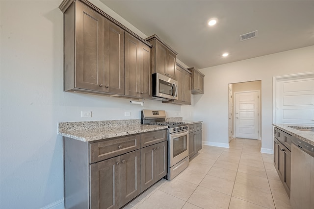 kitchen featuring sink, stainless steel appliances, light stone counters, and light tile patterned flooring