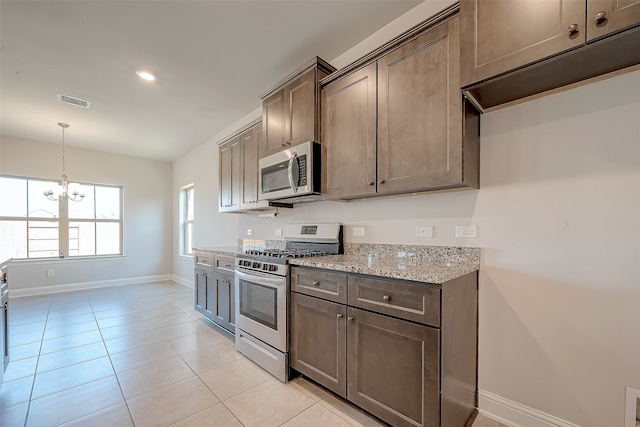 kitchen with light stone countertops, appliances with stainless steel finishes, a chandelier, hanging light fixtures, and light tile patterned flooring