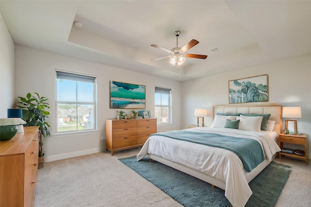 carpeted bedroom with a tray ceiling and ceiling fan