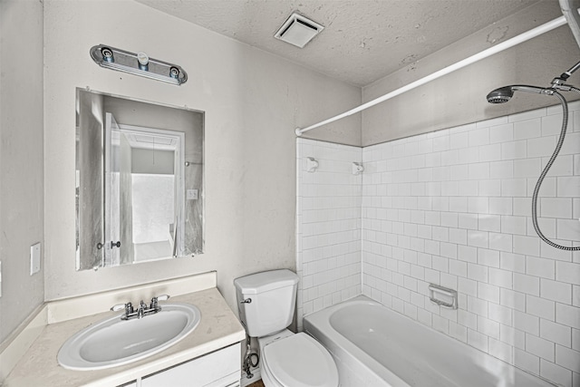 full bathroom featuring vanity, toilet, a textured ceiling, and tiled shower / bath combo