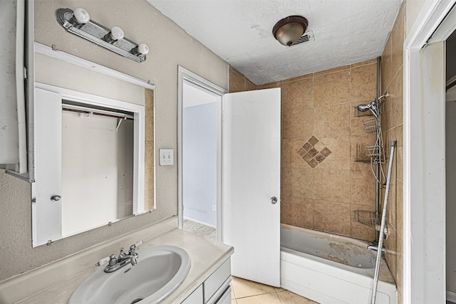 bathroom featuring tiled shower / bath combo, vanity, a textured ceiling, and tile patterned flooring