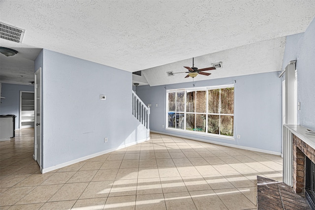 unfurnished living room with ceiling fan, a textured ceiling, light tile patterned floors, a brick fireplace, and vaulted ceiling