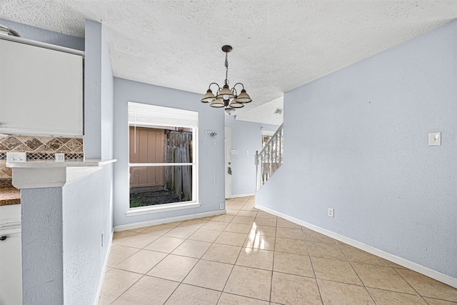 unfurnished dining area featuring a textured ceiling, light tile patterned floors, and a notable chandelier