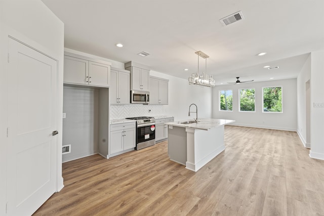 kitchen featuring pendant lighting, a kitchen island with sink, light hardwood / wood-style flooring, ceiling fan, and stainless steel appliances