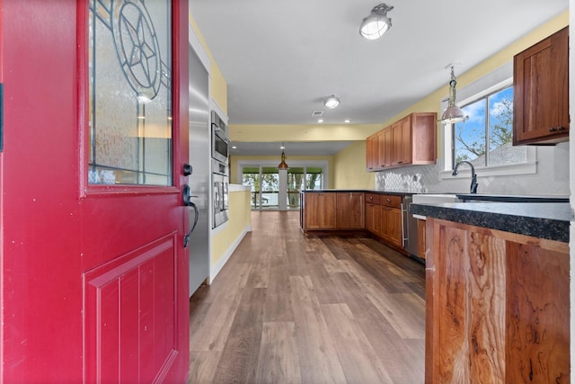 kitchen with dark countertops, backsplash, stainless steel oven, a peninsula, and dark wood-style flooring