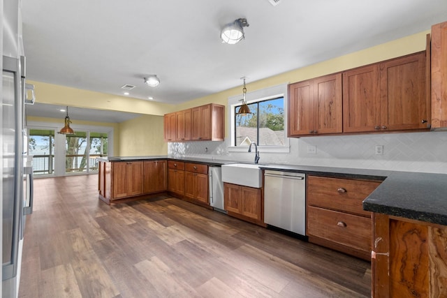 kitchen featuring dark wood-type flooring, brown cabinets, a peninsula, stainless steel dishwasher, and a sink