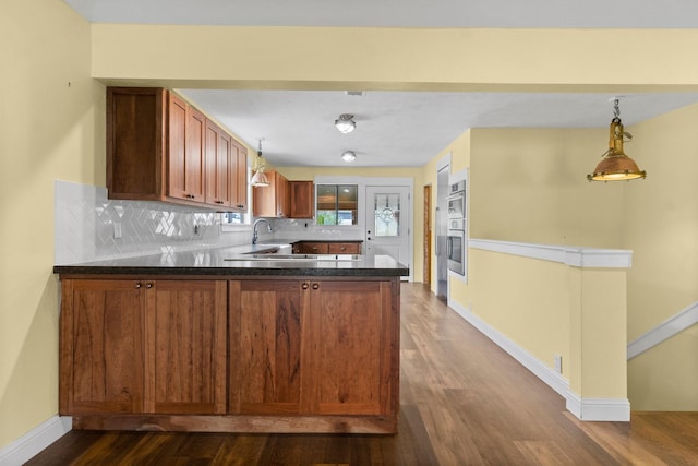 kitchen featuring tasteful backsplash, dark wood finished floors, a peninsula, and baseboards