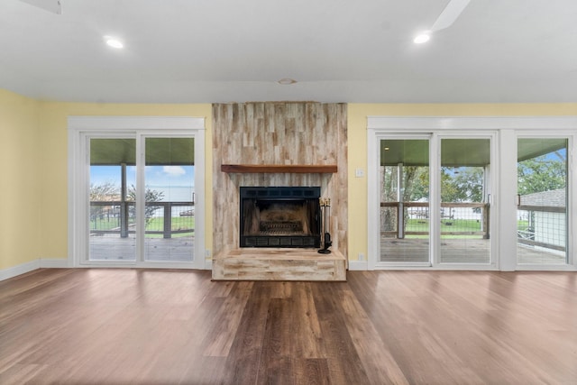 unfurnished living room featuring wood finished floors, baseboards, a ceiling fan, a fireplace, and recessed lighting
