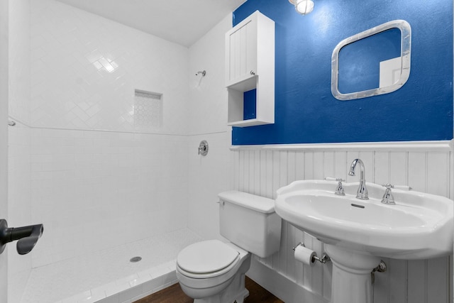 bathroom featuring toilet, a stall shower, and wainscoting
