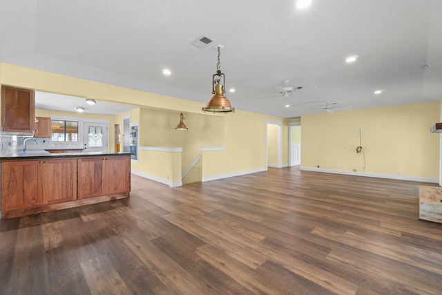 kitchen with stainless steel double oven, hanging light fixtures, sink, decorative backsplash, and dark wood-type flooring