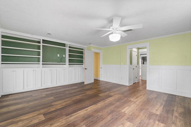 unfurnished room with dark wood-type flooring, ornamental molding, ceiling fan, and built in shelves