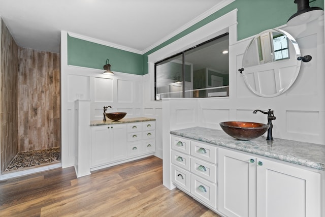 bathroom with wood walls, hardwood / wood-style flooring, walk in shower, ornamental molding, and vanity