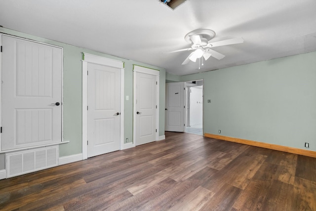 unfurnished bedroom featuring visible vents, two closets, a ceiling fan, wood finished floors, and baseboards