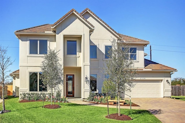 view of front facade featuring a front lawn, decorative driveway, fence, and stucco siding