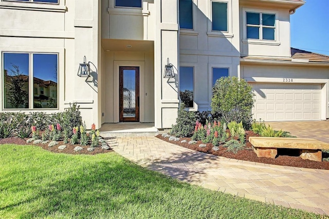 view of exterior entry with a garage and a lawn