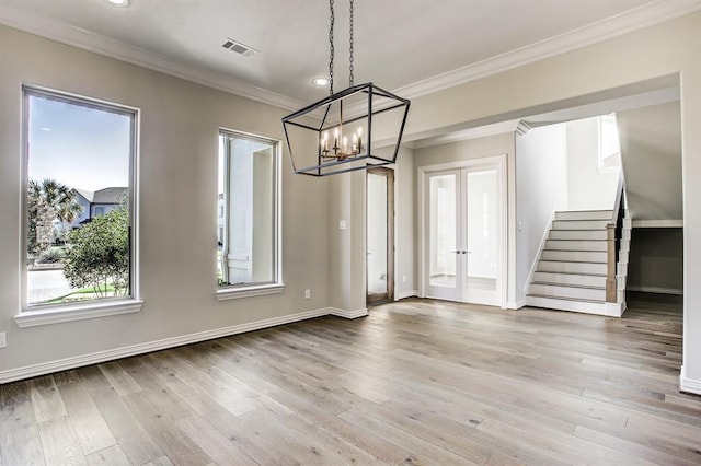 unfurnished dining area with ornamental molding, light hardwood / wood-style flooring, an inviting chandelier, and french doors