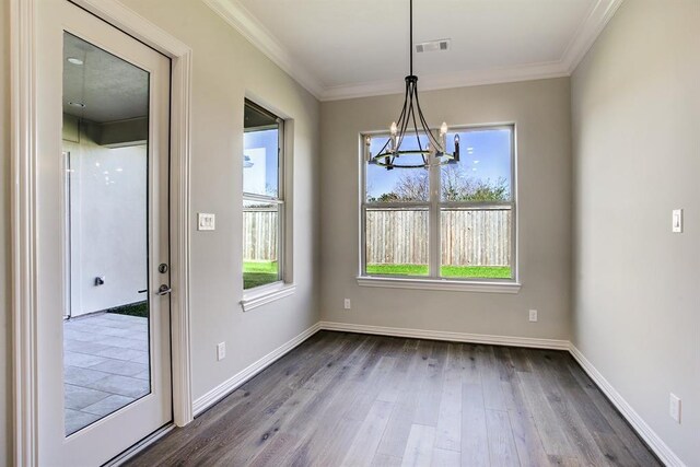 unfurnished dining area with wood-type flooring, a notable chandelier, and crown molding