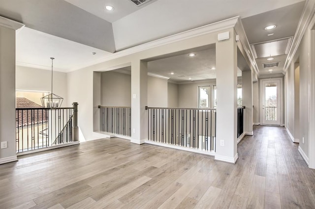 corridor with an inviting chandelier, crown molding, and light hardwood / wood-style flooring