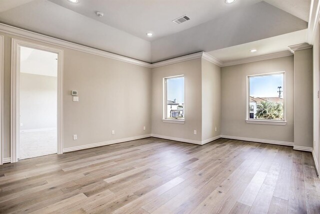 spare room featuring crown molding, a wealth of natural light, and light wood-type flooring