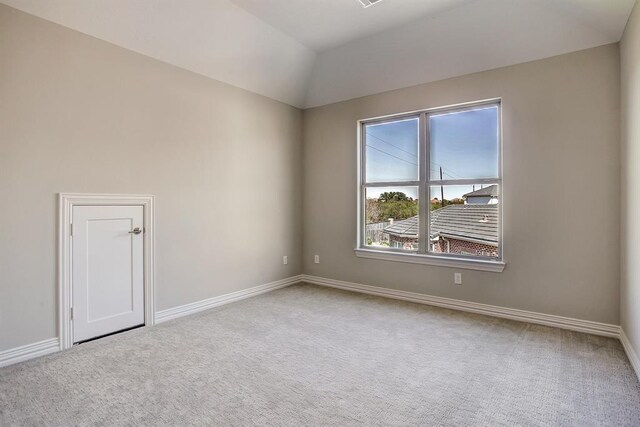 carpeted empty room featuring lofted ceiling