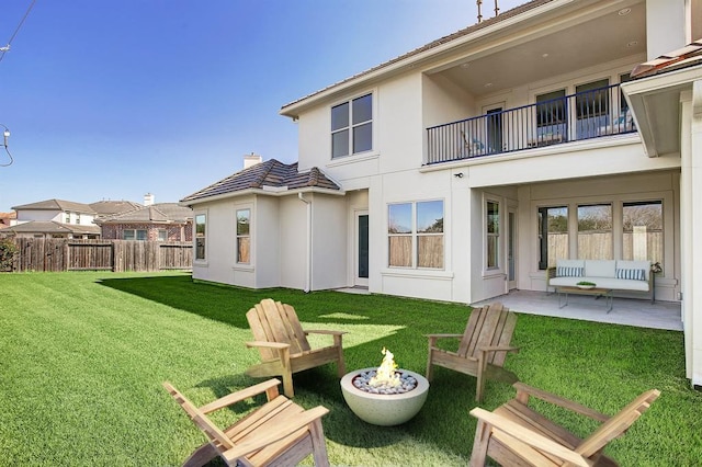 rear view of house featuring a patio, a lawn, and a fire pit