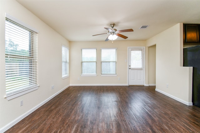 unfurnished living room with ceiling fan, dark wood-type flooring, and a healthy amount of sunlight