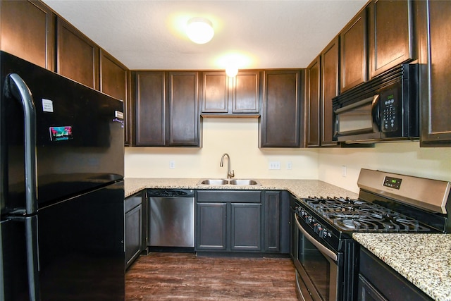 kitchen featuring light stone countertops, dark brown cabinetry, dark wood-type flooring, sink, and black appliances