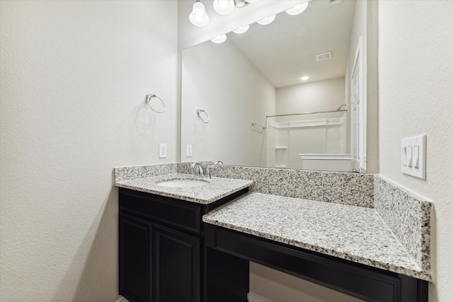 bathroom featuring a shower and vanity