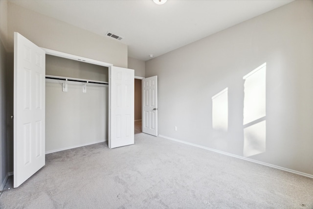 unfurnished bedroom featuring light carpet and a closet