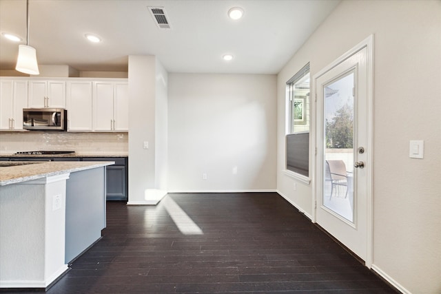 kitchen with light stone counters, white cabinetry, appliances with stainless steel finishes, decorative light fixtures, and dark hardwood / wood-style floors