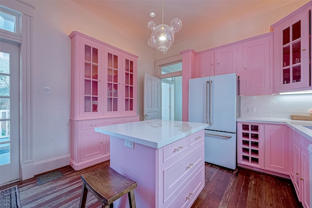 kitchen featuring dark wood-type flooring, a center island, hanging light fixtures, backsplash, and high end white fridge