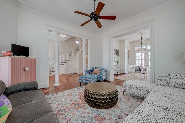 living room featuring wood-type flooring, ornate columns, ceiling fan with notable chandelier, and ornamental molding