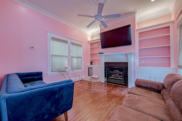 living room with built in features, ceiling fan, hardwood / wood-style floors, and ornamental molding