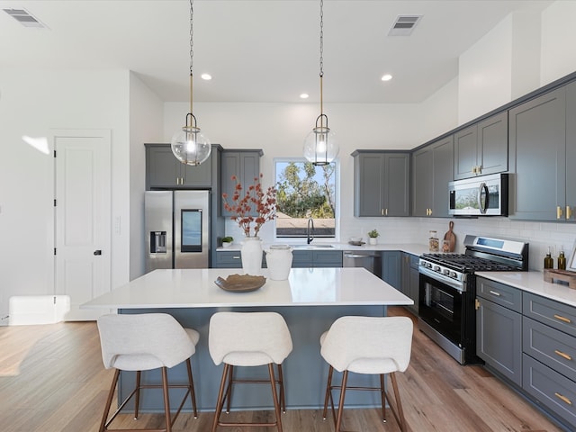 kitchen with gray cabinetry, light wood-type flooring, appliances with stainless steel finishes, and a center island