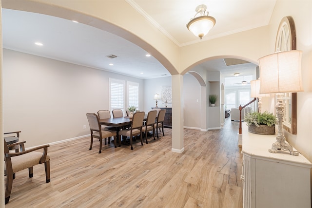 dining space with light wood-type flooring, ornamental molding, and a wealth of natural light