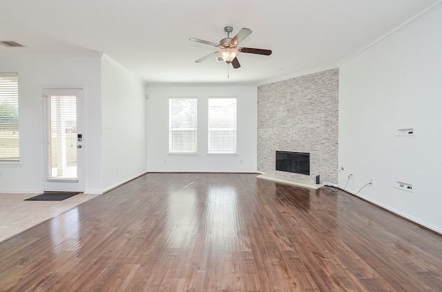 unfurnished living room featuring a stone fireplace, wood-type flooring, ceiling fan, and crown molding