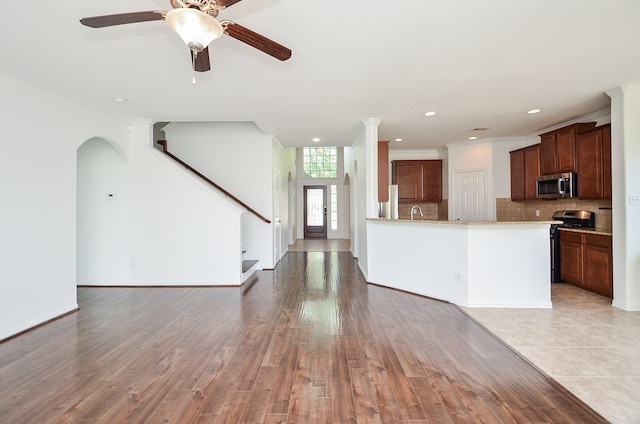 kitchen with stainless steel appliances, tasteful backsplash, light wood-type flooring, and ornamental molding